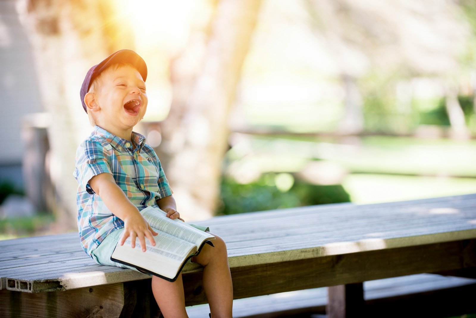 boy sitting on bench while holding a book - Photo by Ben White